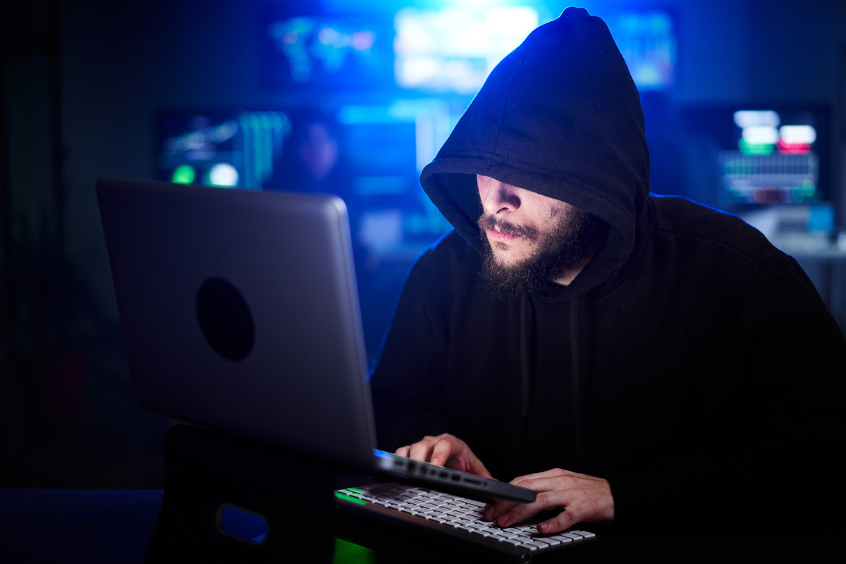 Hidden hacker in sweatshirt and hoodie hacking security systems. Concept of cyber attack and malware